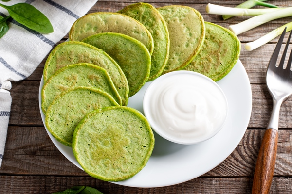 pancakes with spinach and sour cream on a wooden table - Постные капустные блинчики со шпинатом
