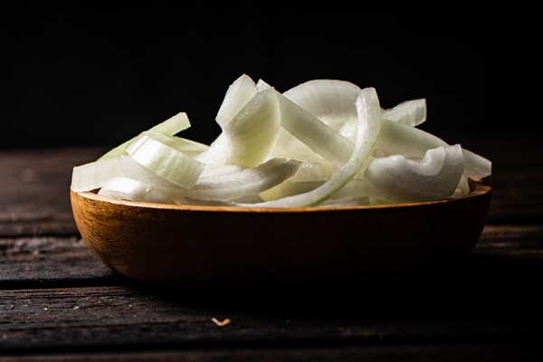 pieces of onion in a wooden plate on the table - Постные пресные блины на картофельном отваре
