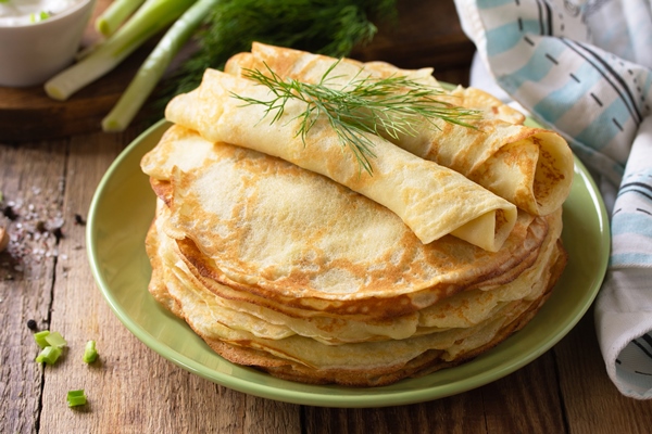 potato pancakes not sweet served with garlic cream sauce on rustic wooden table - Постные картофельные блинчики