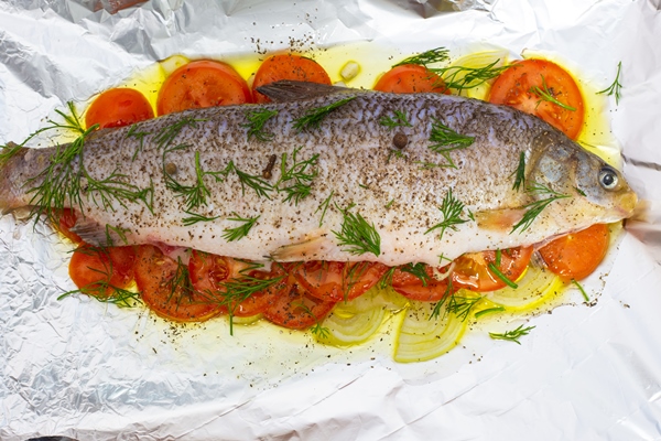 raw fish prepared for frying chokur lies on a foil with vegetables - Судак, запечённый с овощами