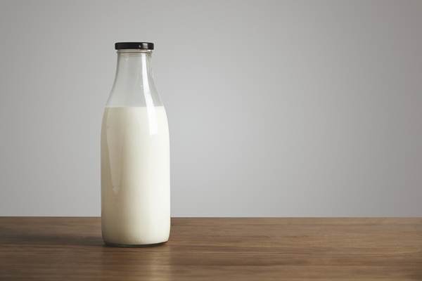 simple vintage bottle filled with fresh milk on thick wooden table closed with black cap cafe shop - Кулич шафранный