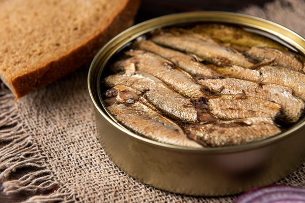 sprats in a tin can and bread on wooden table - Салат «Шпротный»