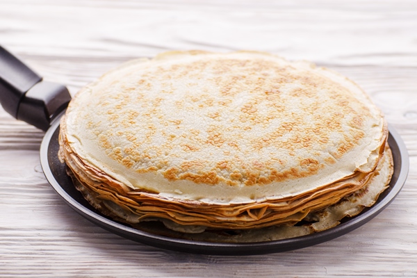 stack of french crepes in frying pan on wooden kitchen table - Постные блины на фасолевом отваре