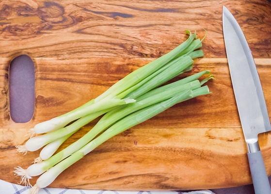 step by step slicing green onions on a wood cutting board - Салат «Сытный»