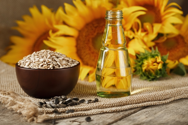 sunflower oil in a glass bottle with seeds in a cup and flowers on a wooden table 1 - Оладьи с кабачком