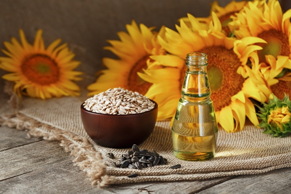 sunflower oil in a glass bottle with seeds in a cup and flowers on a wooden table - Жаворонки постные ванильные