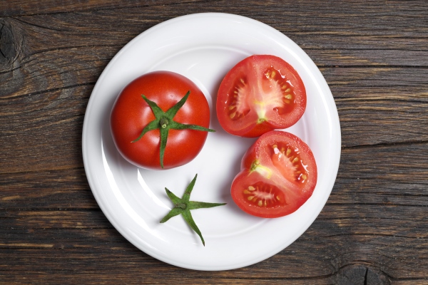 tomatoes and sliced in plate on dark wooden background top view - Салат с полуострым перцем и помидорами