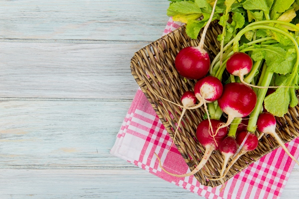 top view of radishes in basket plate on plaid cloth on right side and wooden background with copy space - Салат из редиса с лимонным соком
