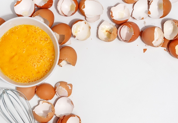 whipping eggs with whisk yolks and egg protein in a cup corolla whisk eggs preparation of food and chicken eggs eggshell on a table view from above - Баба кружевная
