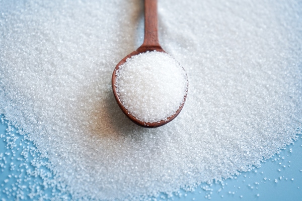 white sugar in wooden spoon on sugar background with selective focus 1 - Салат из баклажанов с фасолью на зиму