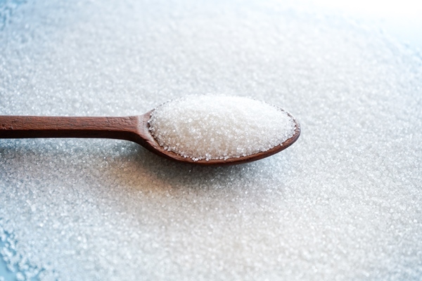 white sugar in wooden spoon on sugar background with selective focus - Постные дрожжевые блины с луком и грибами