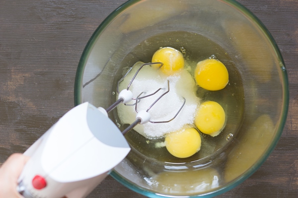 woman hand holding mixer in the glass bowl with sugar and eggs before beating - Баба нежная