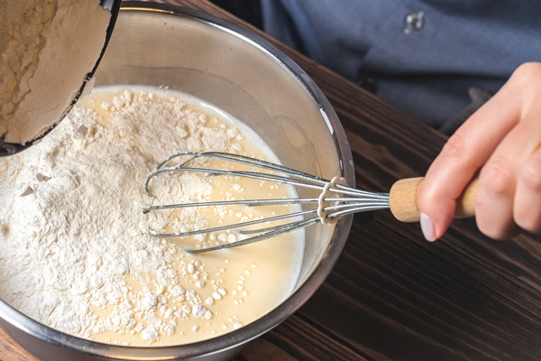 woman kneads dough in a metal bowl preparation of dough for baking pancakes selective focus 1 - Постные блины со свёклой и орешками