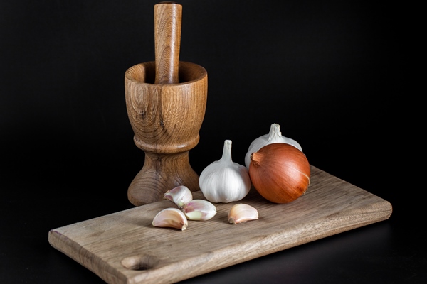 wooden mortar pounder pestle onion garlic and other vegetables on black kitchen tools - Салат из перца и баклажанов