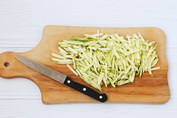 zucchini cut into thin strips arranged on a wooden board on white background top view - Кабачковая икра диетическая