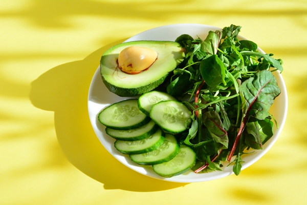 avocado with cucumber slices and salad greens on the plate on the yellow background - Смузи с семенами льна