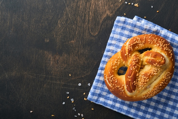 bavarian pretzels and glass of lager beer oktoberfest food menu traditional salted pretzels over old dark wooden background top view with space for text oktoberfest theme - Постный именинный крендель