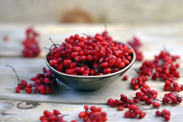 berries and bunches of barberry in a bowl on a wooden surface - Кисель из барбариса