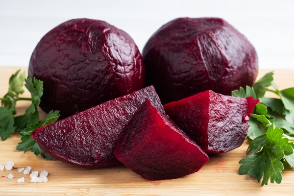 boiled beets whole and cut on a cutting board with parsley leaves on a white background - Постная фаршированная свёкла под соусом