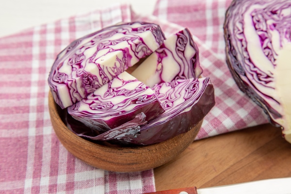 bottom close view red cabbage in bowls purple white checkered kitchen towel on cutting board on grey table - Салат из красной капусты в маринаде