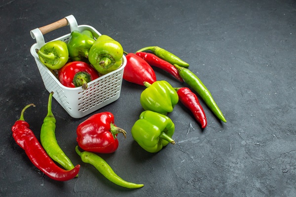 bottom view green and red peppers in plastic basket hot peppers on dark background with free space - Салат из перца с яблоком