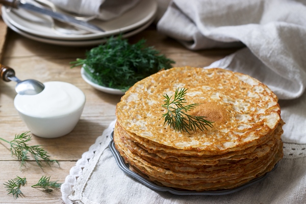 buckwheat pancakes served with sour cream and dill on a wooden table rustic style - Русские постные блины гречнево-пшеничные