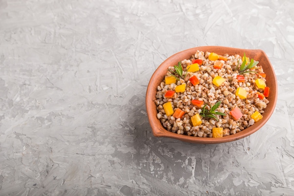 buckwheat porridge with vegetables in clay bowl on a gray concrete surface side view copy space - Гречневая каша с овощами