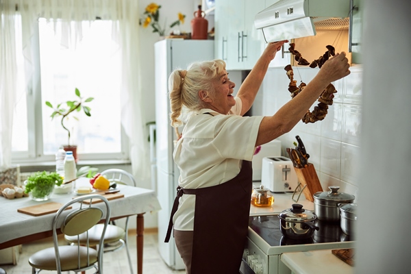 cheerful old woman checking dried mushrooms in kitchen - Постная гречневая каша