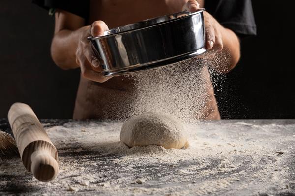 chef dusting flour over dough - Пирог или пирожки с вареньем