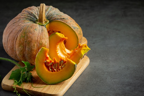 chopped raw pumpkin put on wooden cutting board - Пшённая каша с тыквой