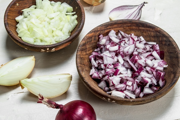 chopped red and yellow onions in a bowl on rustic - Салат картофельный с редькой