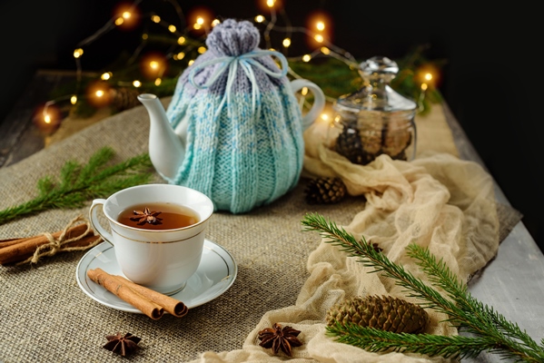 christmas composition with a cup of tea and a teapot covered with a heating pad - Чай лимонный