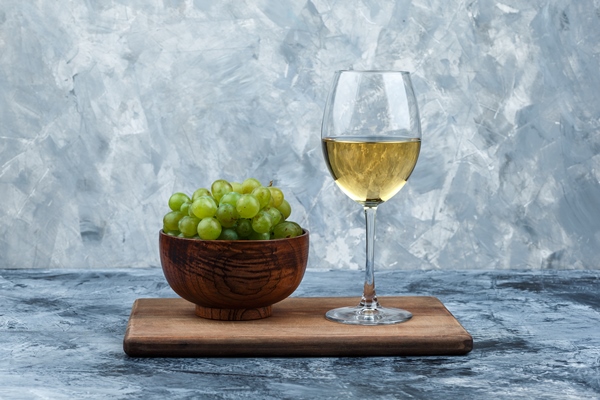 close up bowl of white grapes glass of whisky on cutting board on dark and light blue marble background horizontal - Картофельный салат с рисом и рыбой