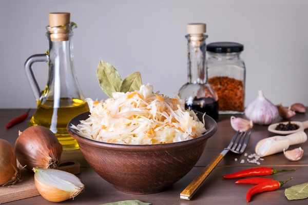 close up of sauerkraut fermented cabbage in ceramic sauerkraut bowl on table with spices and ingredients healthy healthy food russian kitchen selective focus - Пирог с кислой капустой и грибами