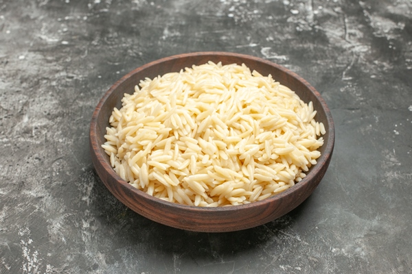 close up on boiled rice in a brown wooden pot - Картофельный салат с рисом и рыбой
