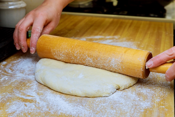 closeup of hands using rolling pin on dough - Пирог «Луковник» постный