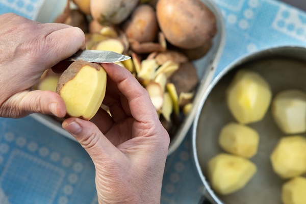 closeup of woman hands peeling potatoes with a kitchen knife - Постный суп из консервов
