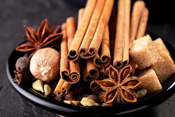 collection of spices for mulled wine and pastry on black background - Оладьи с пряностями и специями