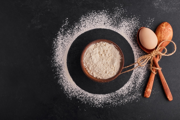 crossed wooden spoons with an egg inside and a cup of flour around - Овсяные блины с ягодами и фруктами
