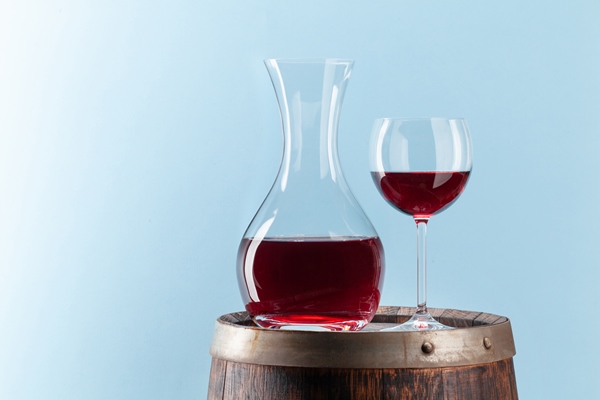 decanter with red wine on old wooden barrel - Маседуан из смеси свежих плодов