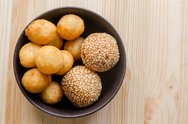 deep fried sweet potato balls in black bowl on wooden table - Картофельные орешки