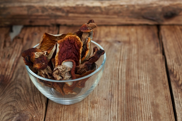 dried boletus edulis mushrooms in a bowl on the wooden table - Тушёная кислая капуста