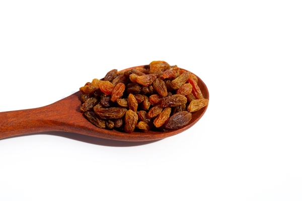 dried grape raisins in wooden spoon on white background - Квас из ржаного хлеба с мятой и изюмом