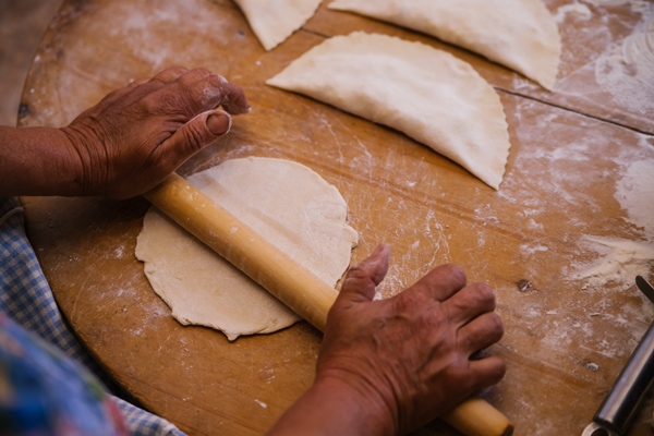 female hands holding a rolling pin in the process of cooking kutaba or chebureks minced meat and onions in doughcottage cheese and onion in the dough azerbaijani tatar caucasian greek cuisine - Чебуреки постные
