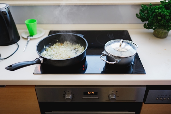 finely chopped onions are fried in a pan frying pan and pan on an induction stove - Баклажаны, тушённые со свежими помидорами и луком