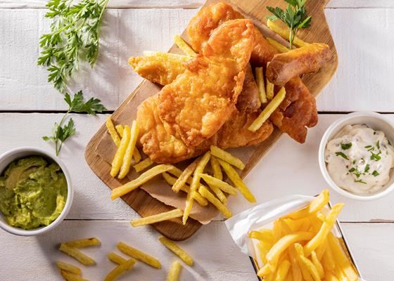 flat lay of fish and chips on chopping board with sauce - Рыба жареная или печёная