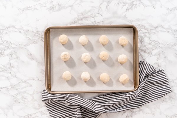 flat lay rising frozen dinner rolls on a baking sheet lined with parchment paper - Булки постные