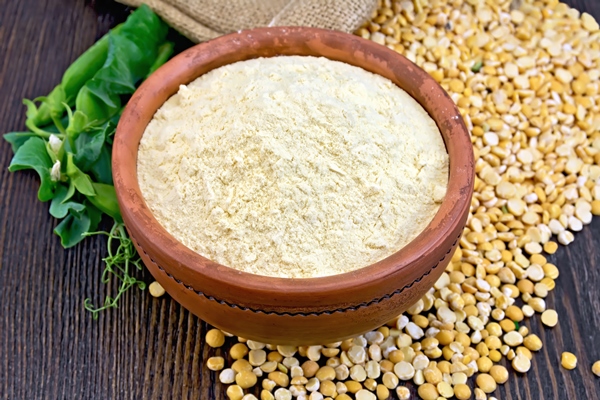 flour pea in a clay bowl flakes and fresh pods on a background of wooden boards - Постный гороховый кисель