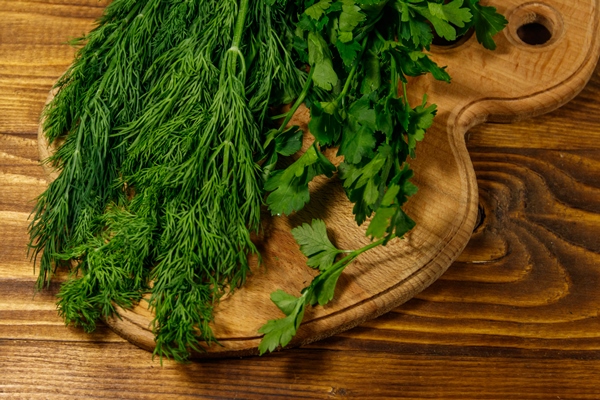 fresh green dill and parsley on cutting board on wooden table - Картофель с патиссонами