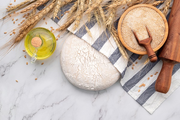 fresh homemade yeast dough resting on marble table with ears of wheat and rolling pin - Тесто на дрожжах заварное